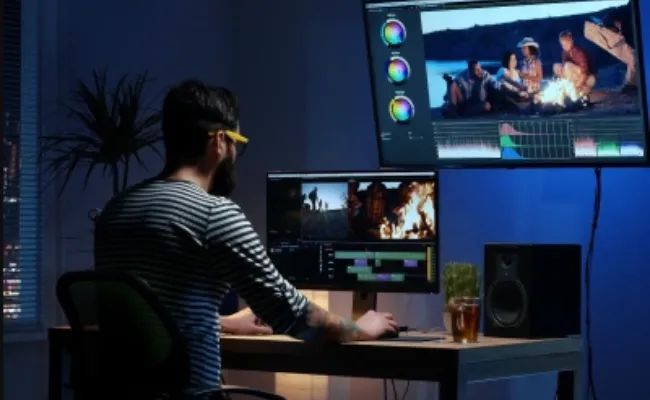 Video editor working in a studio on a multi-screen setup to refine footage for a documentary film, illustrating expert video post-production and professional video editing services.