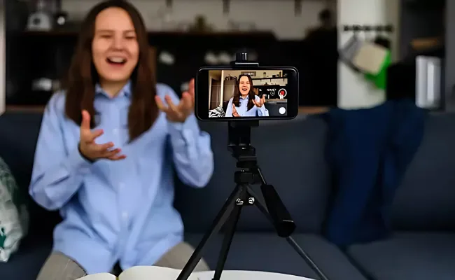 Female content creator recording a video on smartphone for YouTube, ideal for professional video editing services offered by a video editing company.