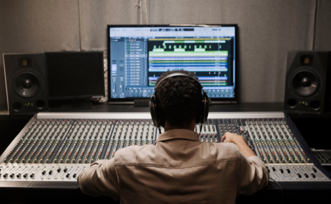 Audio engineer working at a mixing console with waveform editing software on screen, performing noise reduction and voice-over synchronization as part of YouTube video editing services.