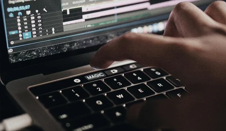 Close-up of a video editor working on wedding footage using editing software on a laptop, showcasing professional wedding video editing services.