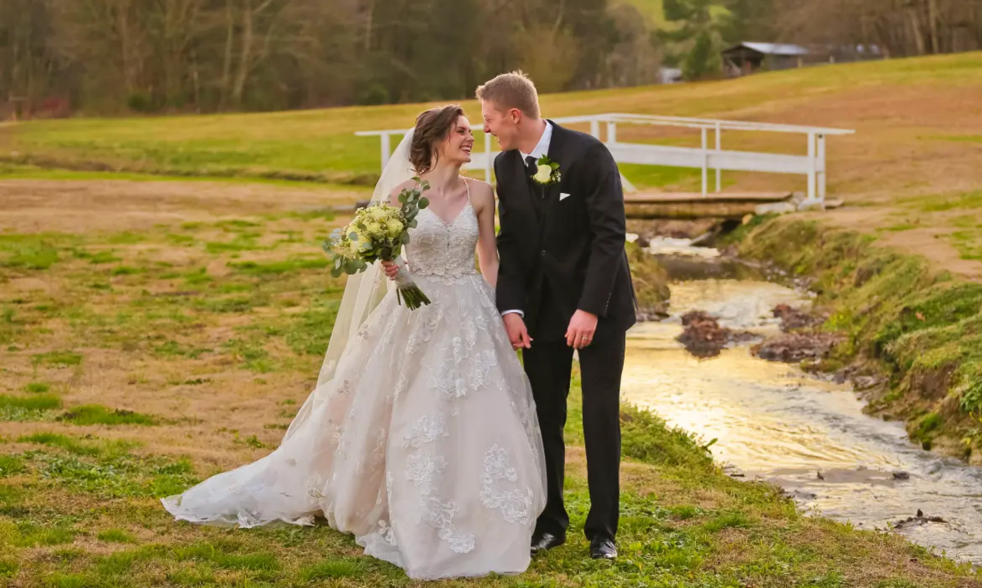 Happy bride and groom sharing a romantic moment outdoors near a small stream, ideal footage for wedding highlight reels and social media teaser trailers.