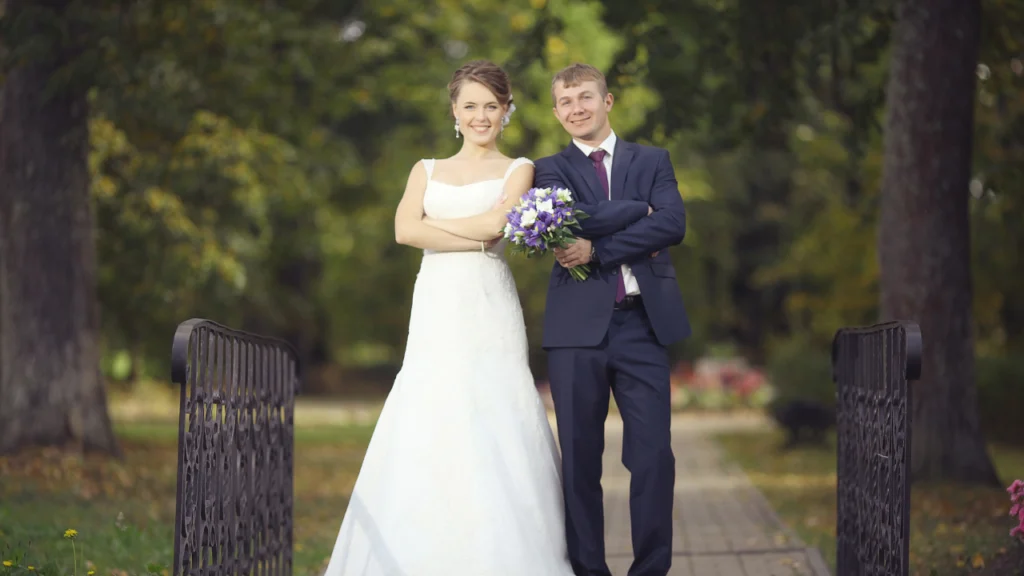 Bride and groom smiling while standing on a garden bridge, representing the importance of understanding a couple’s wedding vision and asking the right questions before the big day for personalized videography planning