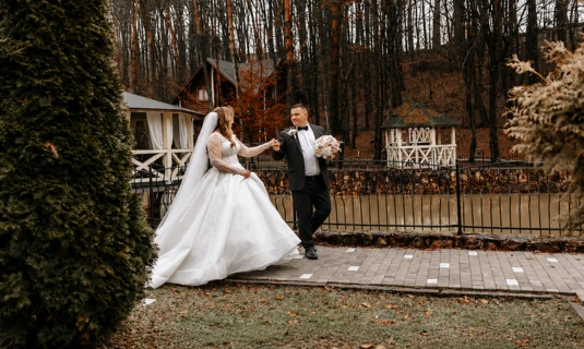 Bride and groom holding hands outside a rustic wedding venue, highlighting full-length documentary wedding film editing services.