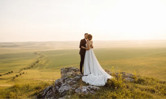 Bride and groom embracing on a hilltop during a pre-wedding shoot, showcasing cinematic pre-wedding video editing services for engagement films and save-the-date videos.