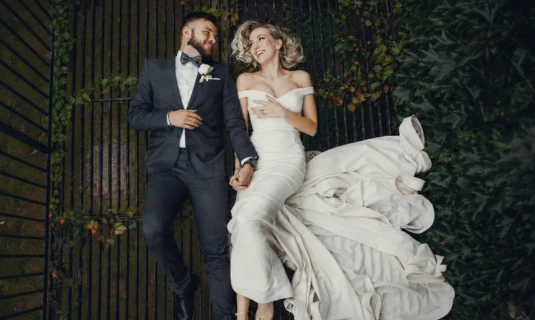 Bride and groom holding hands and laughing in wedding attire, showcasing wedding film editing services for teasers and social media reels.